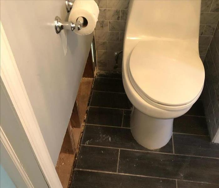 a bathroom toilet with the baseboards removed from the walls