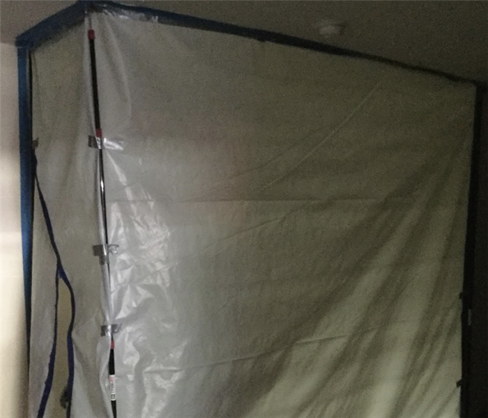 a white tarp set up blocking off an area in a room